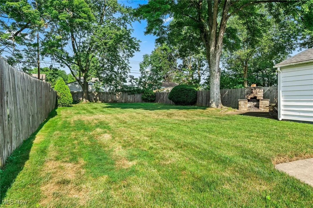 View of large fenced backyard offering privacy and a fireplace