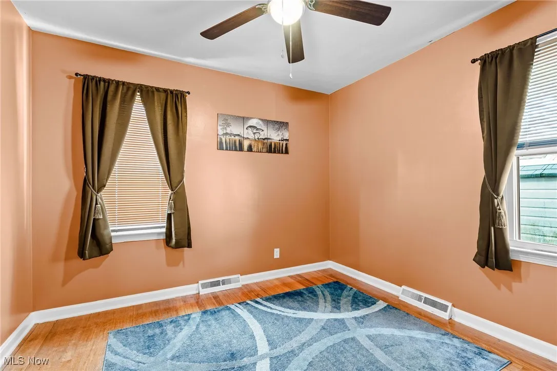 Bedroom 2 on the main floor featuring beautifully refinished hardwood floors, newer windows, newer ceiling fan