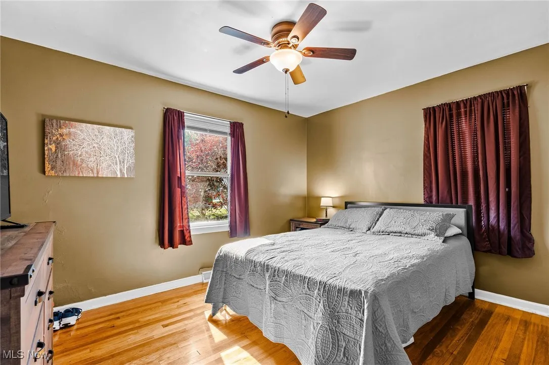 Bedroom 1 of 2 on the main floor featuring beautifully refinished hardwood floors, newer windows, newer ceiling fan