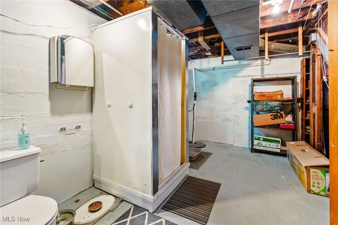 Unfinished area of the Basement with a toilet and shower, sump pump, and waterproofing system. Bathroom area can easily be framed in and finished into a private space.
