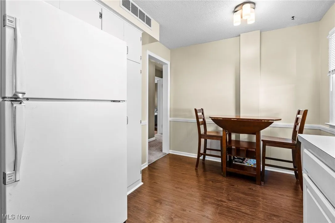 Dining area of the eat-in Kitchen featuring newer laminate floors, white appliances, newer windows, and newer light fixtures