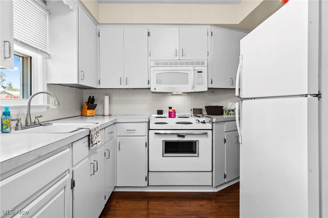 Eat-in Kitchen with tile backsplash, electric range, microwave hood, refrigerator, and newer laminate floors