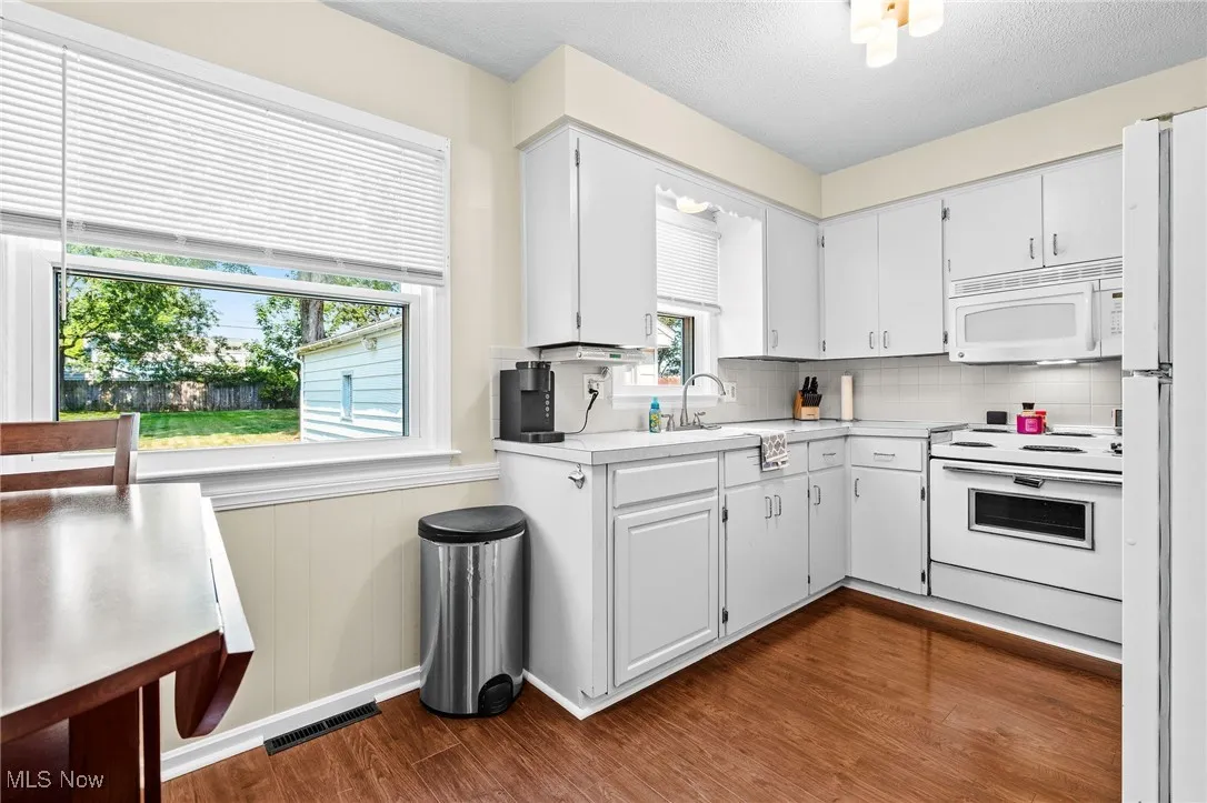 Eat-in Kitchen featuring wainscoting, white appliances (electric range, refrigerator, microwave/hood), and newer lighting and laminate floors