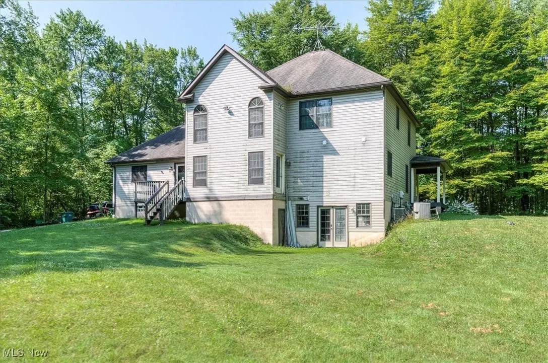 Back of property with a yard, a shingled roof, and stairs