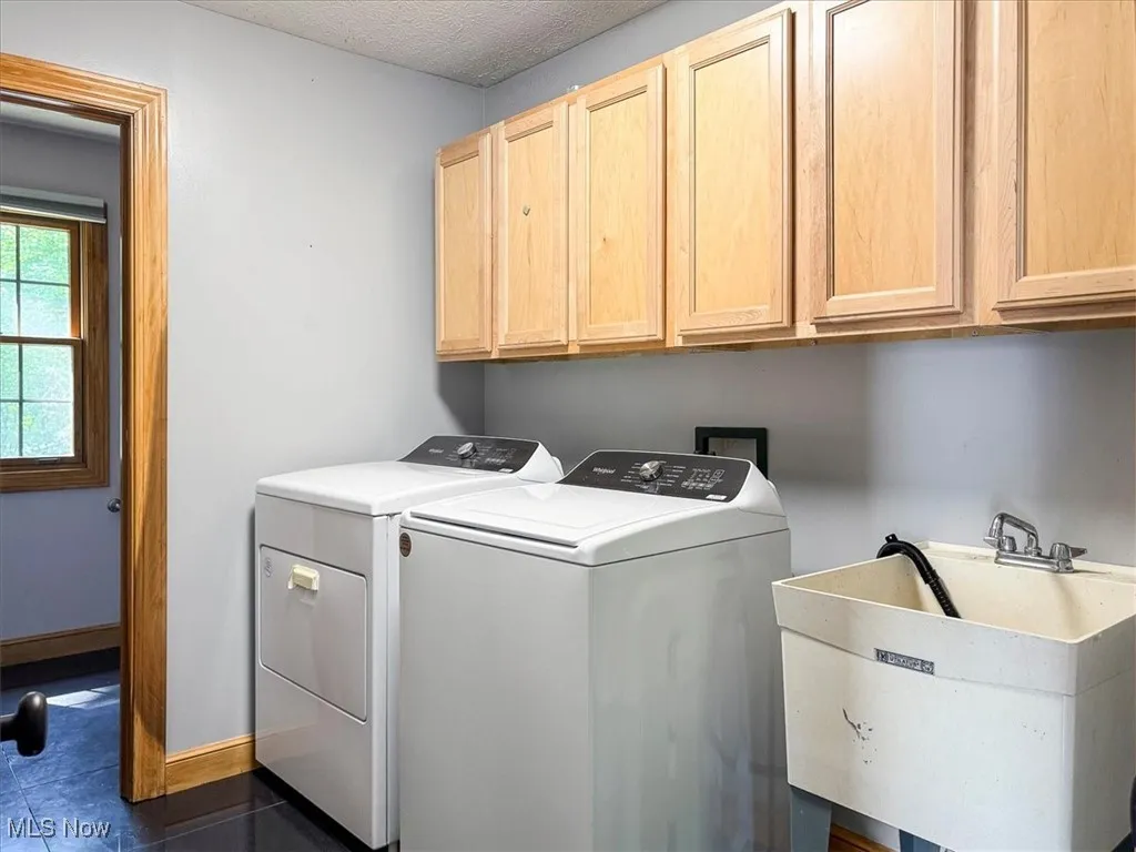 Laundry area featuring cabinet space, washer and clothes dryer, and dark tile patterned floors
