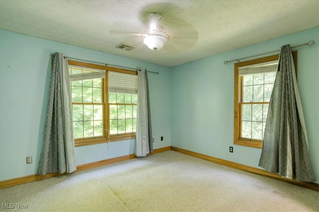 Carpeted spare room with ceiling fan and a textured ceiling