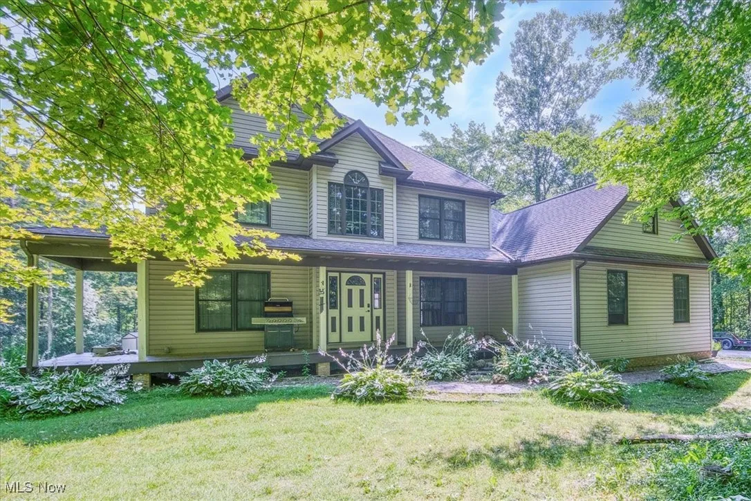 View of front of house with covered porch, a front yard, and a shingled roof