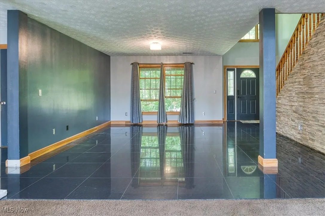 Empty room featuring plenty of natural light, a textured ceiling, and granite tiled floors