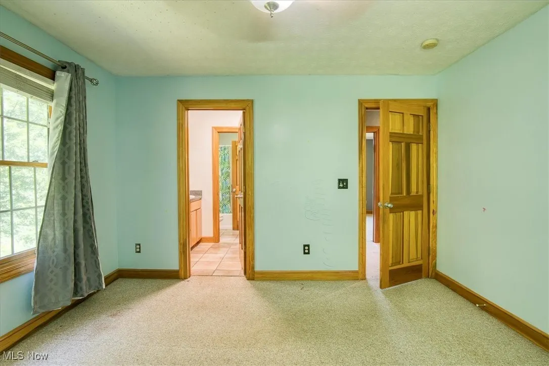 Unfurnished bedroom with carpet and connected bathroom