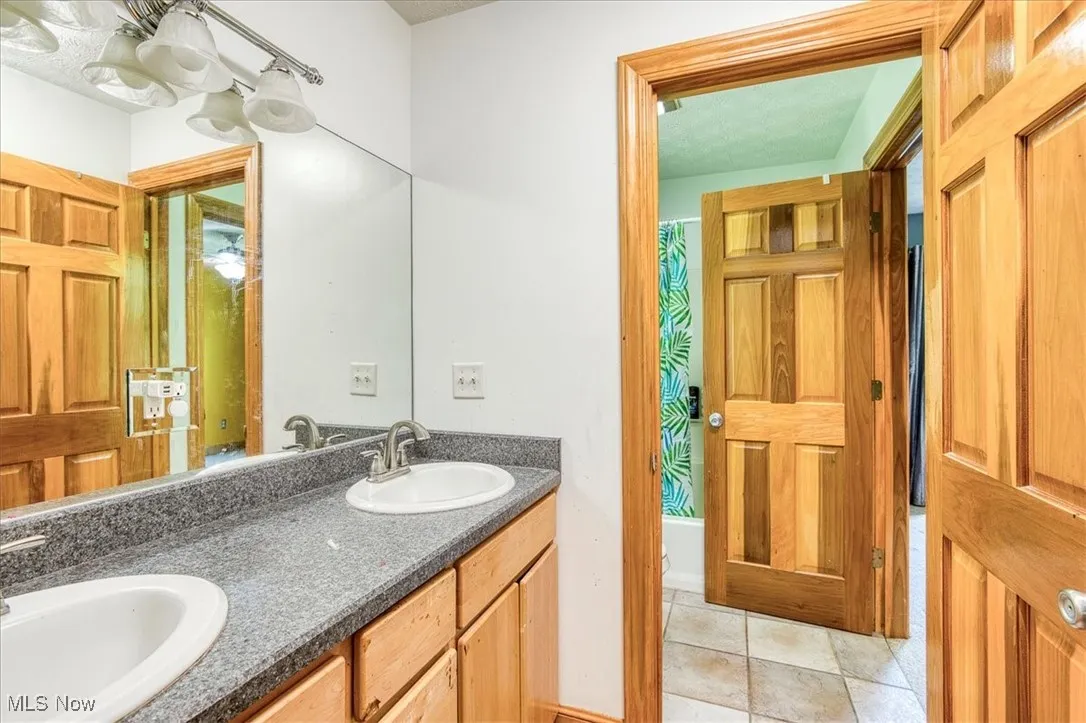 Bathroom featuring double vanity, a shower with curtain, and tile patterned flooring