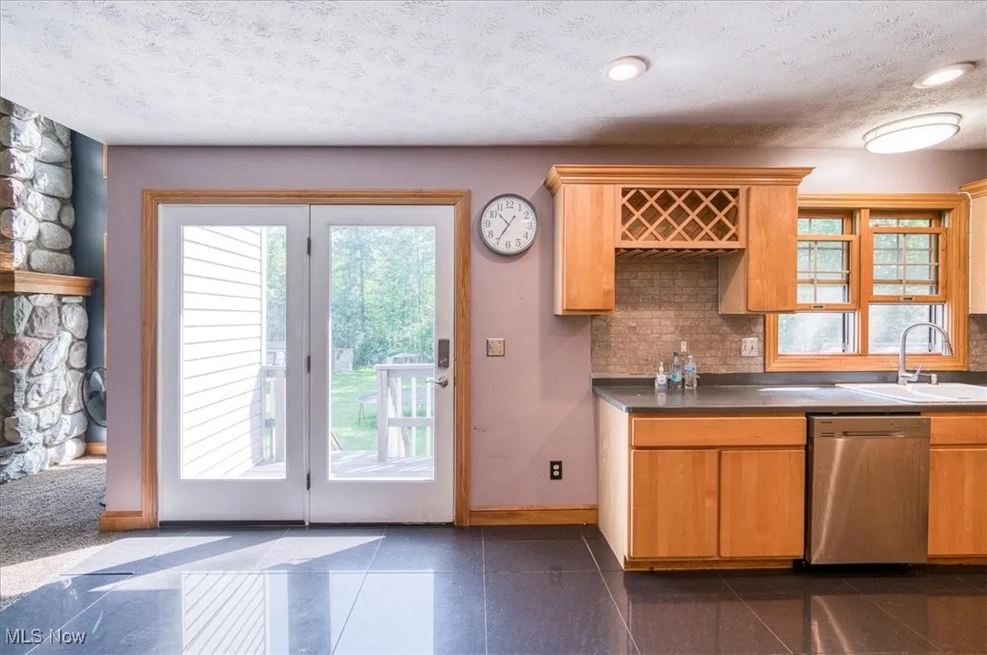 Kitchen with stainless steel dishwasher, backsplash, and a textured ceiling