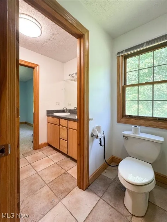 Bathroom with vanity, a textured ceiling, and tile patterned floors