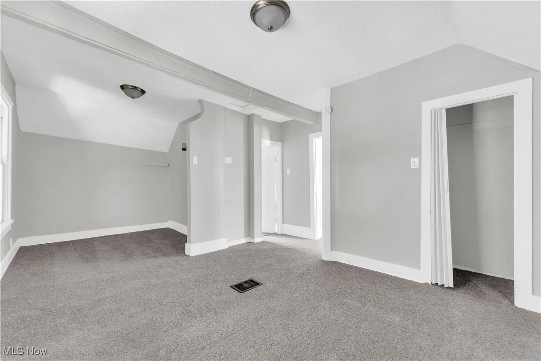 Additional living space featuring carpet flooring and lofted ceiling