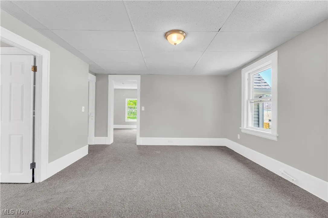 Spare room with a drop ceiling and carpet flooring