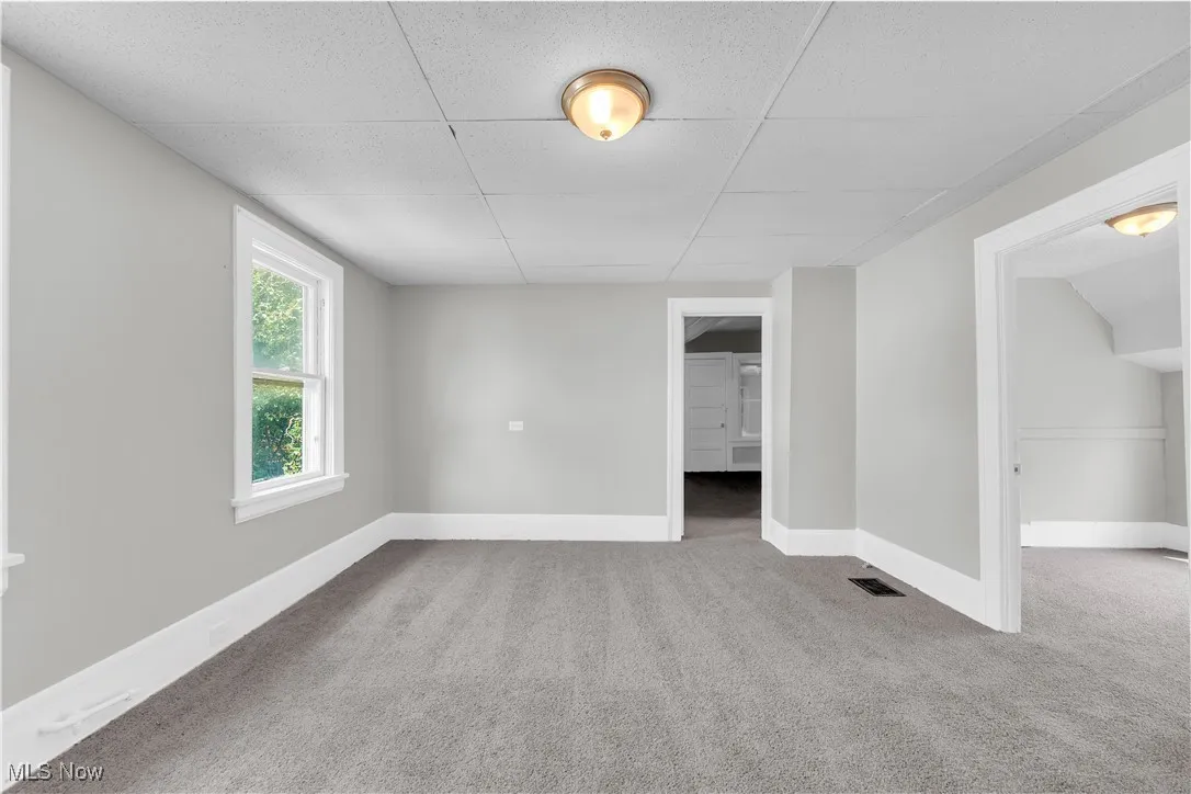 Carpeted spare room with baseboards and a paneled ceiling