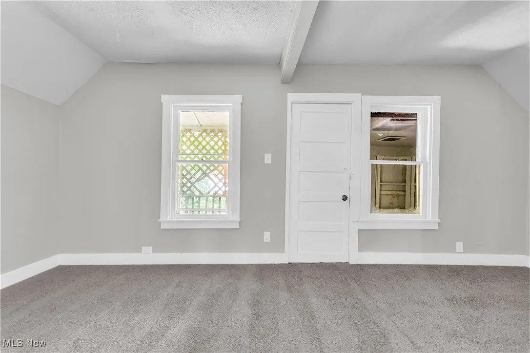 Bonus room with vaulted ceiling, carpet flooring, and a textured ceiling