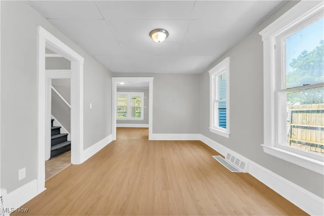 Spare room featuring light wood-type flooring, stairway, and a paneled ceiling