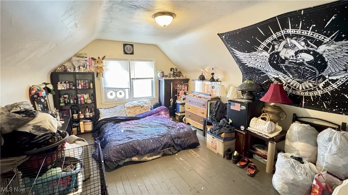 Bedroom featuring hardwood / wood-style floors, vaulted ceiling, and a textured ceiling