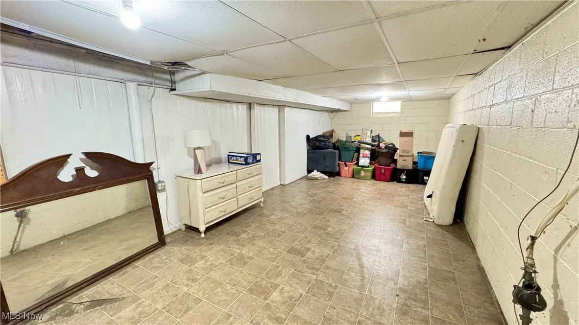 Finished basement with concrete block wall, a drop ceiling, and light flooring