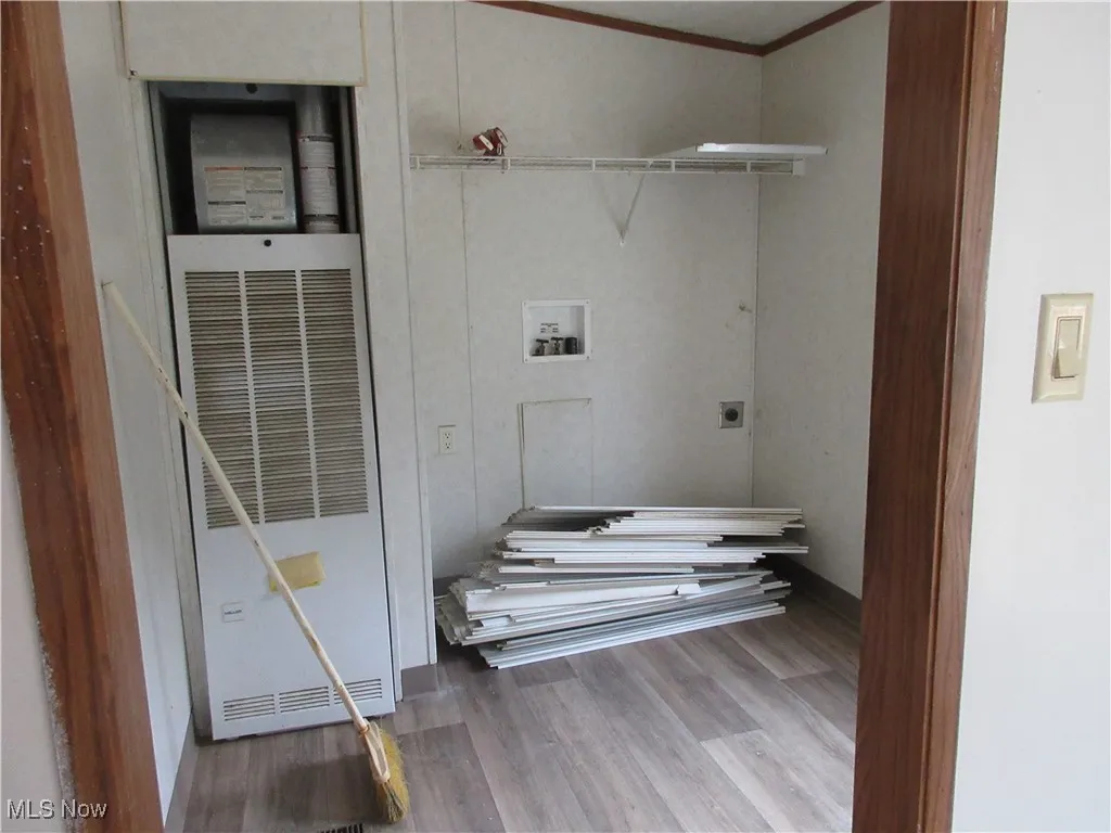 Laundry area with washer hookup, wood finished floors, a heating unit, ornamental molding, and hookup for an electric dryer