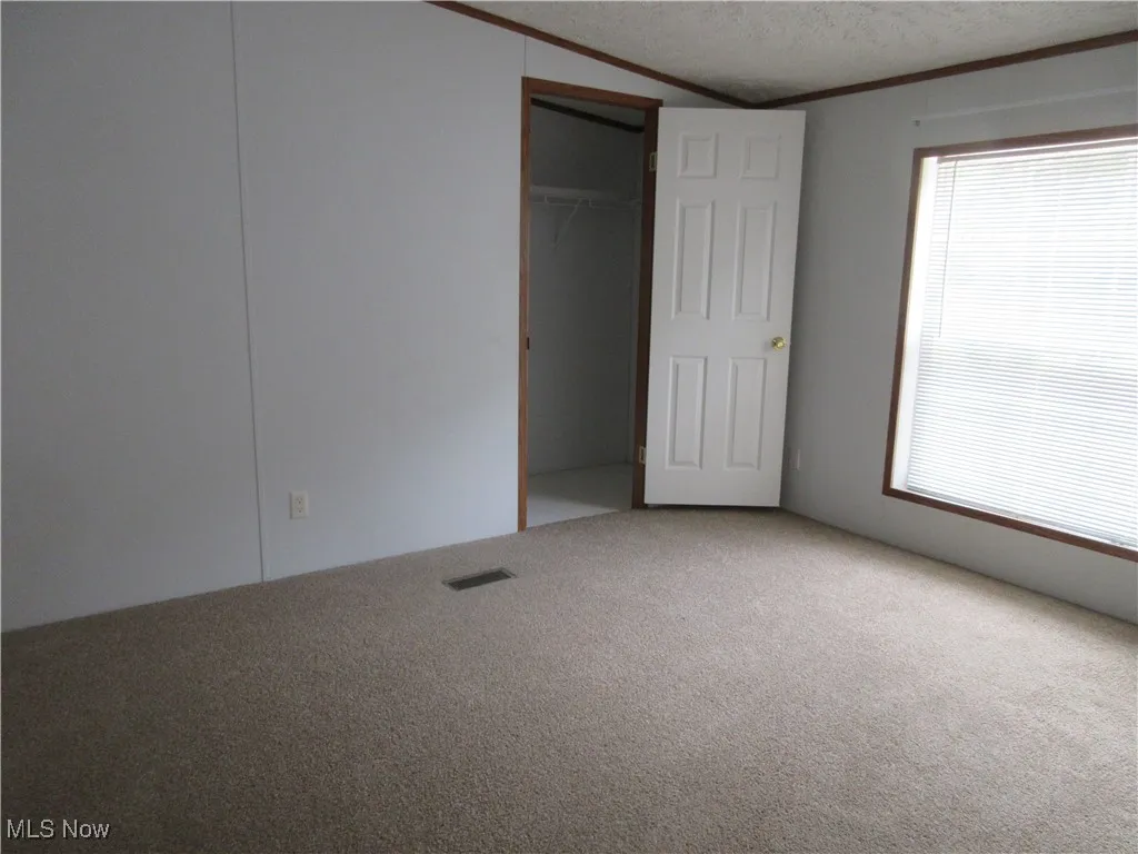 Unfurnished bedroom with carpet floors, crown molding, and a textured ceiling