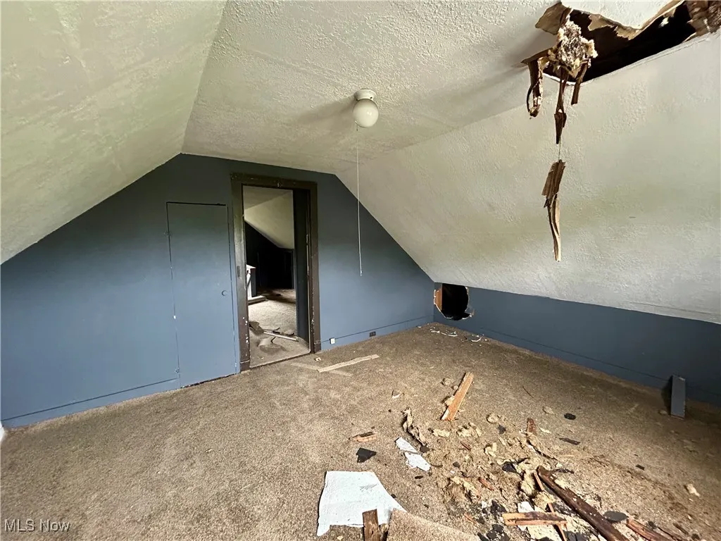 Bonus room with a textured ceiling and lofted ceiling