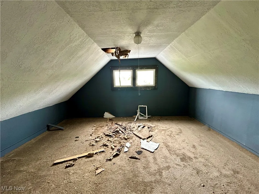 Bonus room with a textured ceiling and vaulted ceiling