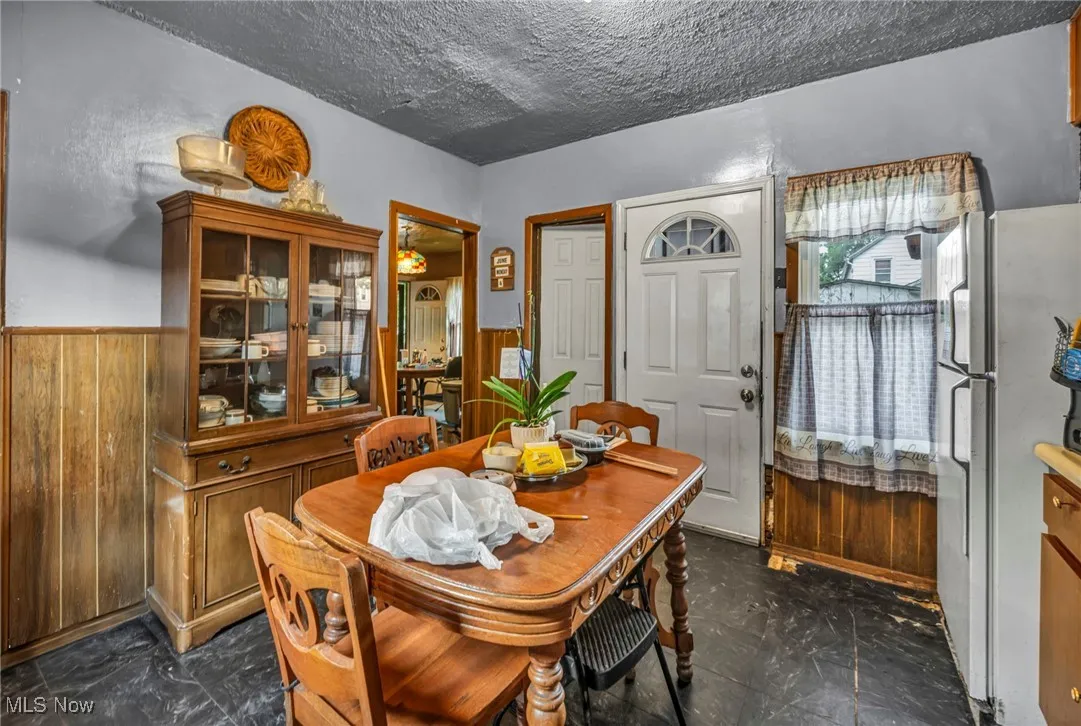 Dining area with wood walls, a textured ceiling, and wainscoting