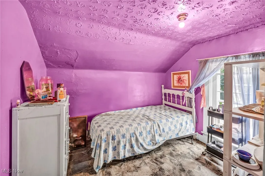 Bedroom featuring lofted ceiling and a textured ceiling