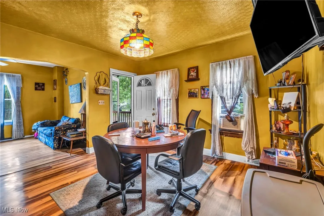 Dining space featuring wood finished floors, a textured ceiling, and arched walkways