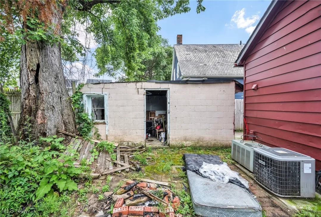 Back of house featuring a chimney and a storage unit
