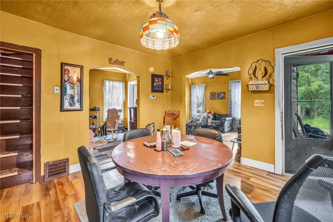 Dining space featuring light wood-style floors, ceiling fan, and arched walkways