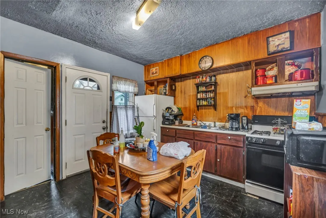 Kitchen featuring white appliances, a textured ceiling, under cabinet range hood, and light countertops