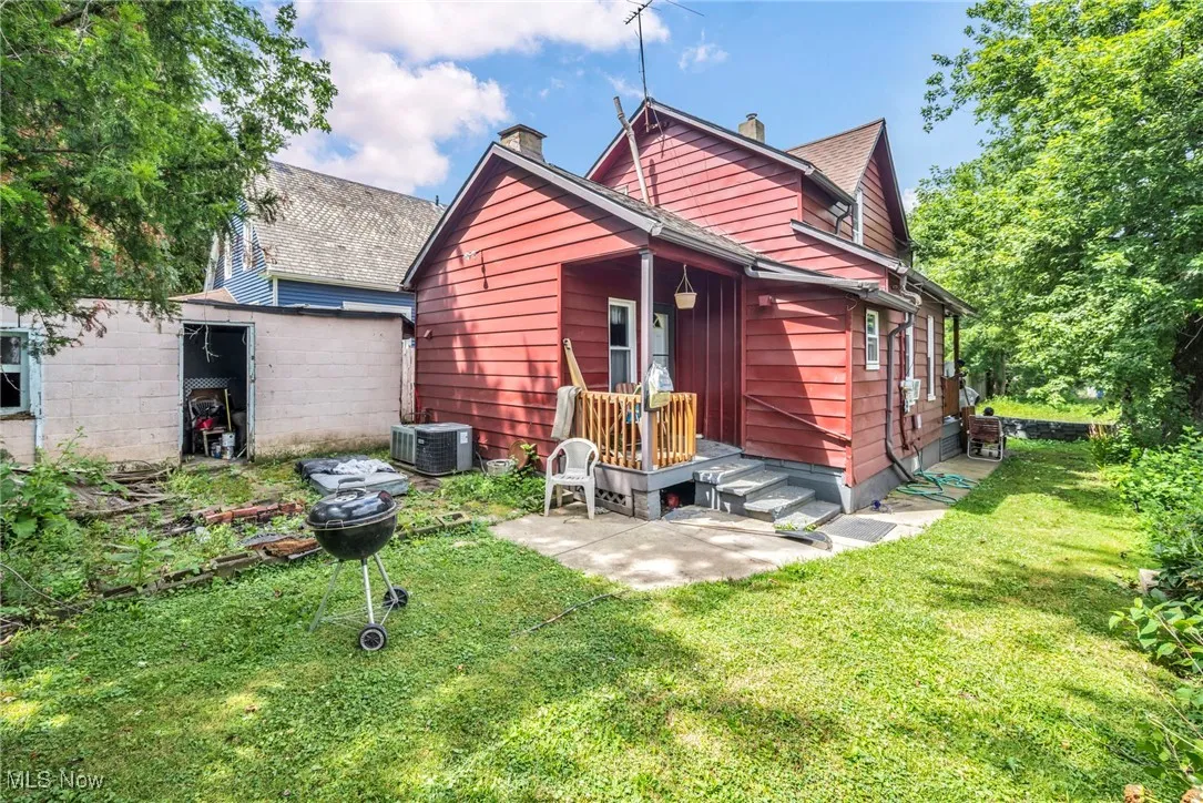 Rear view of house featuring a lawn, a chimney, and a storage shed
