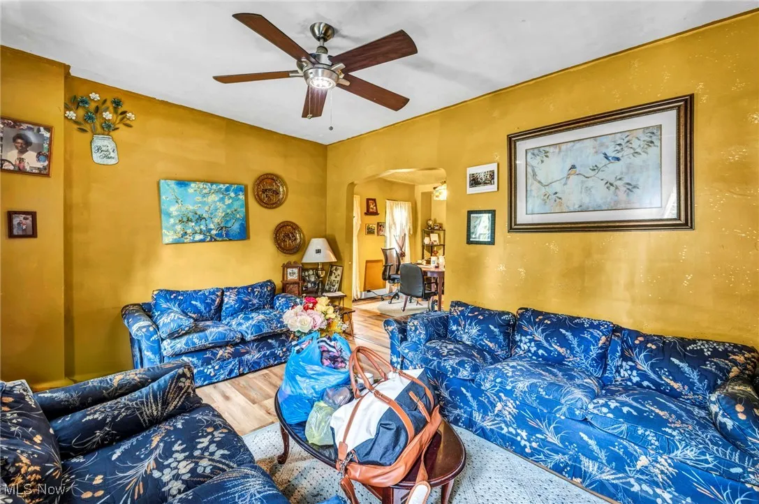 Living room with arched walkways, wood finished floors, and ceiling fan