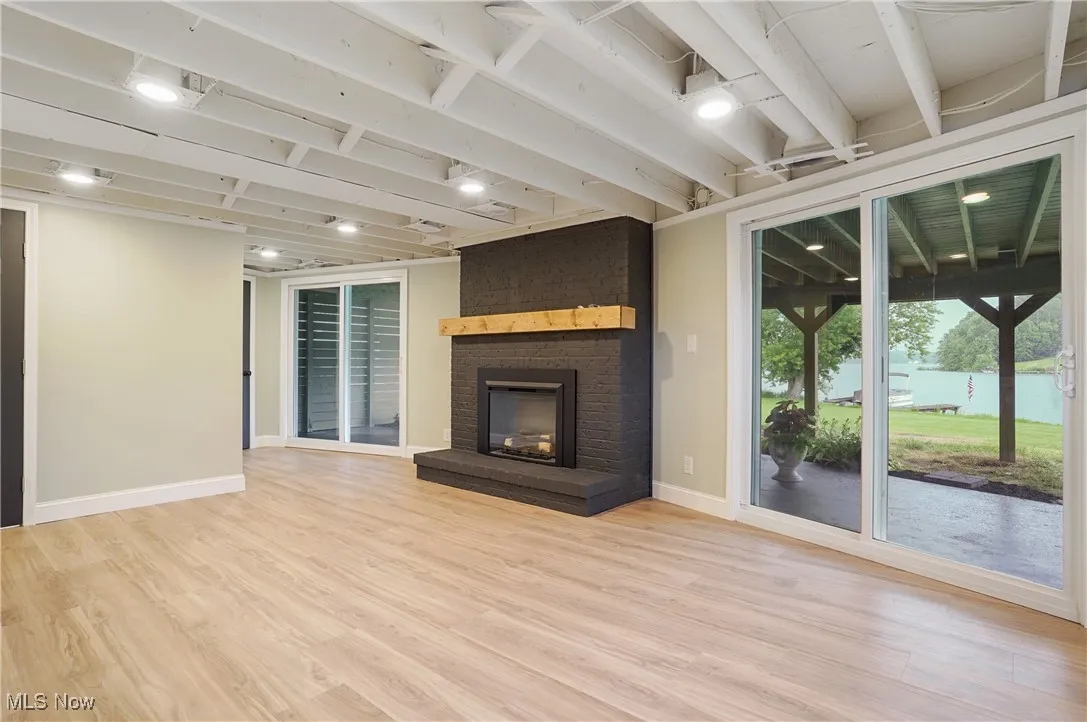 Unfurnished living room featuring light wood-style floors and a brick fireplace