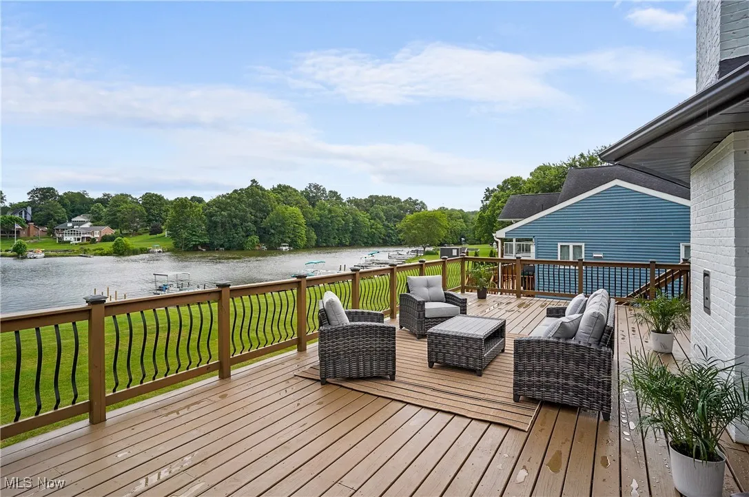 Wooden terrace featuring a water view, an outdoor hangout area, and a lawn