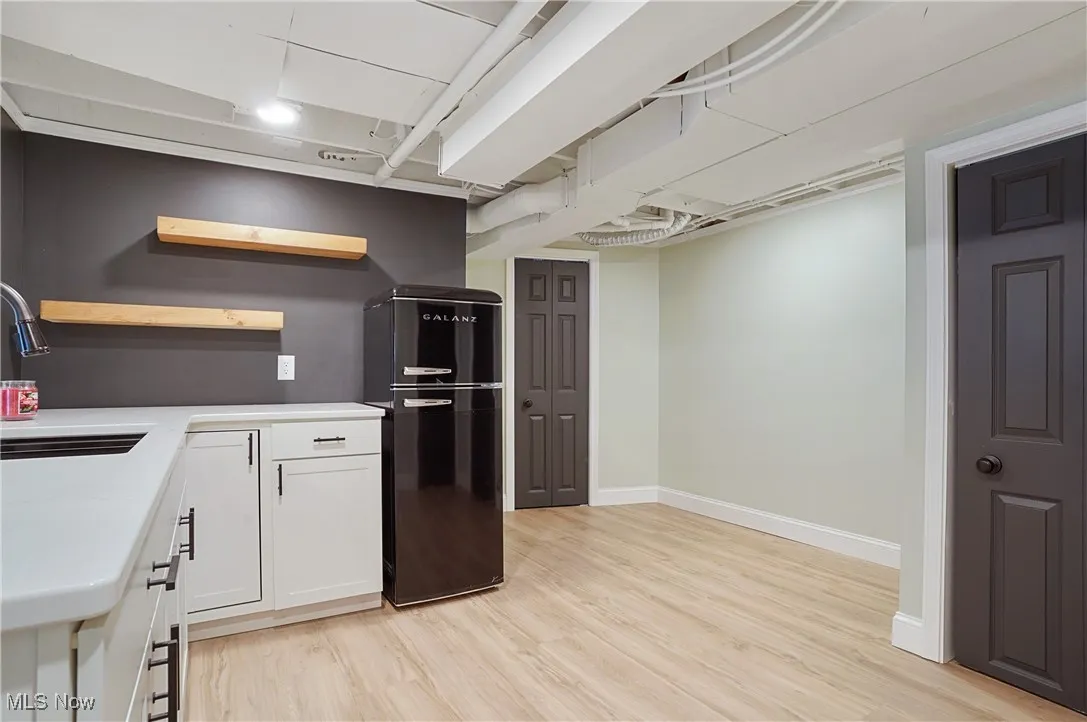 Kitchen featuring freestanding refrigerator, open shelves, white cabinetry, light wood-type flooring, and light countertops