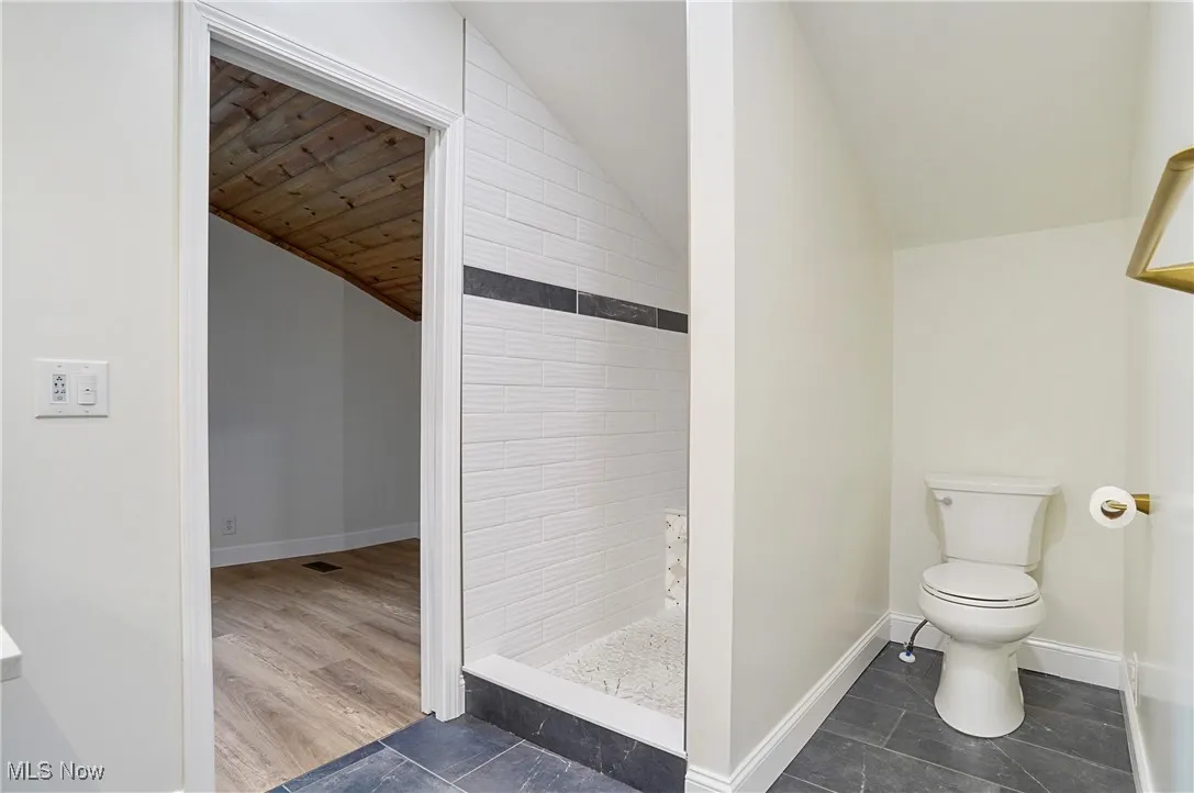Full bathroom with lofted ceiling and a tile shower