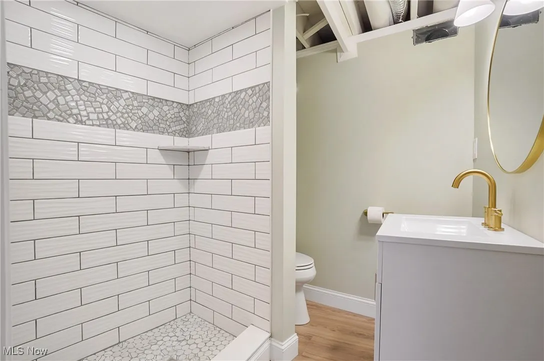 Bathroom with a tile shower, vanity, and wood finished floors