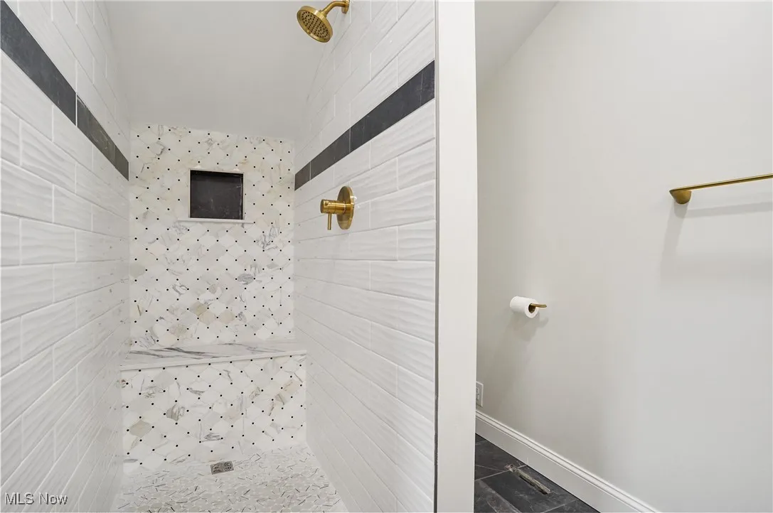 Bathroom featuring tiled shower and baseboards