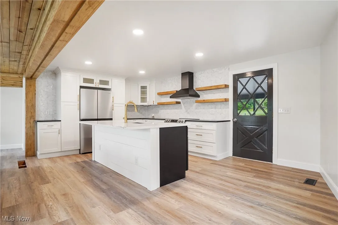 Kitchen featuring open shelves, freestanding refrigerator, light wood-style floors, tasteful backsplash, and recessed lighting