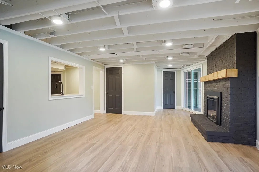 Unfurnished living room with light wood finished floors and a brick fireplace