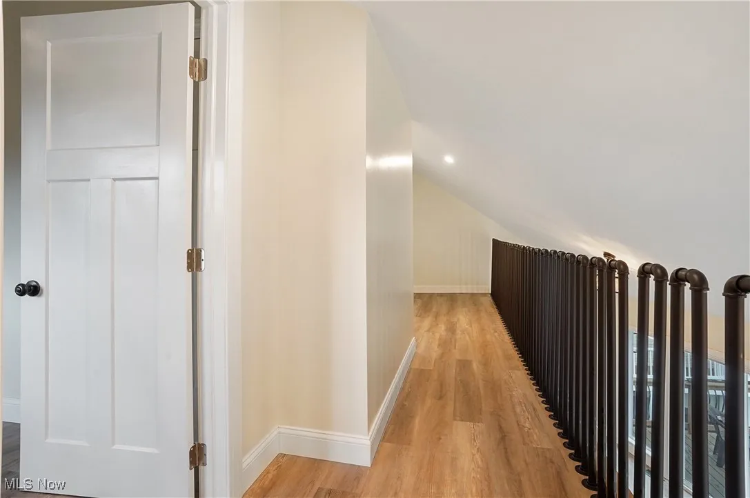 Hallway with wood finished floors and vaulted ceiling
