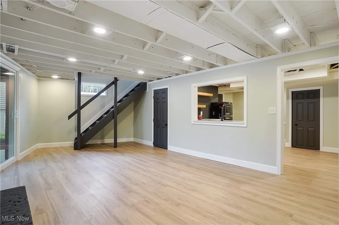 Below grade area with light wood-style flooring, stairway, and fridge