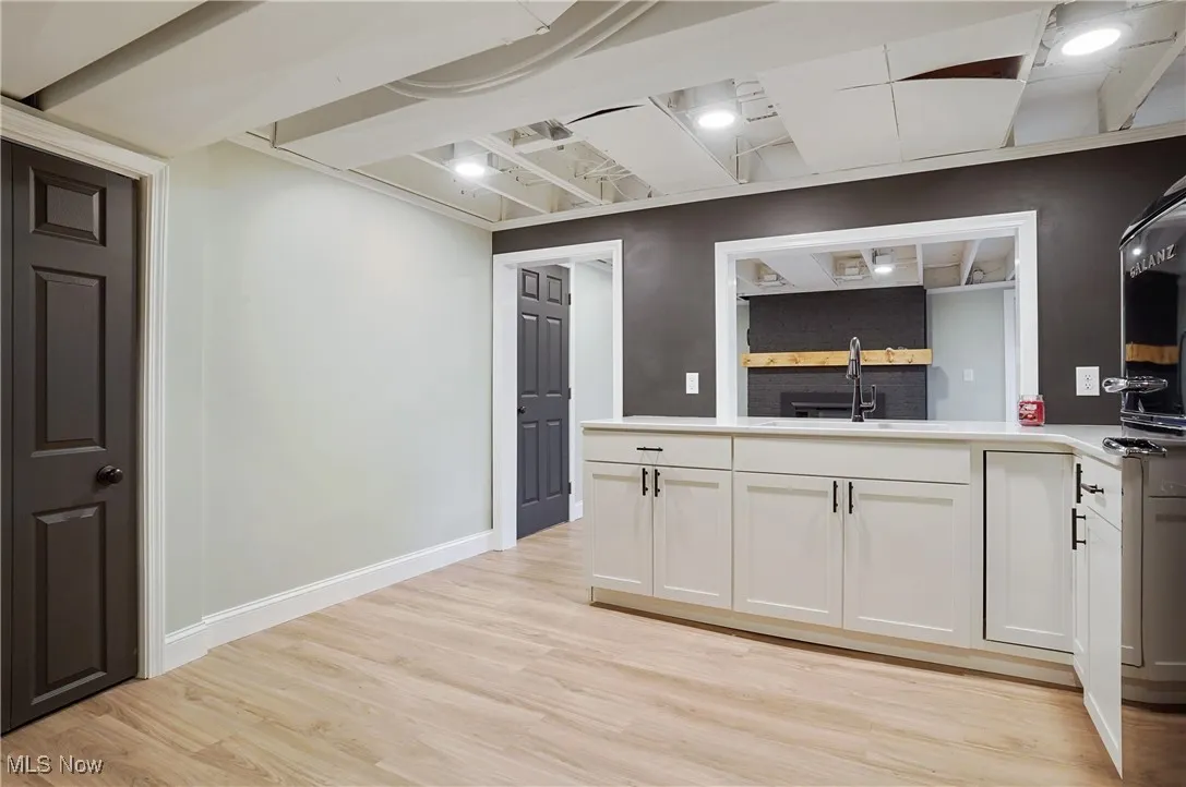 Kitchen with light wood finished floors, white cabinetry, and light countertops