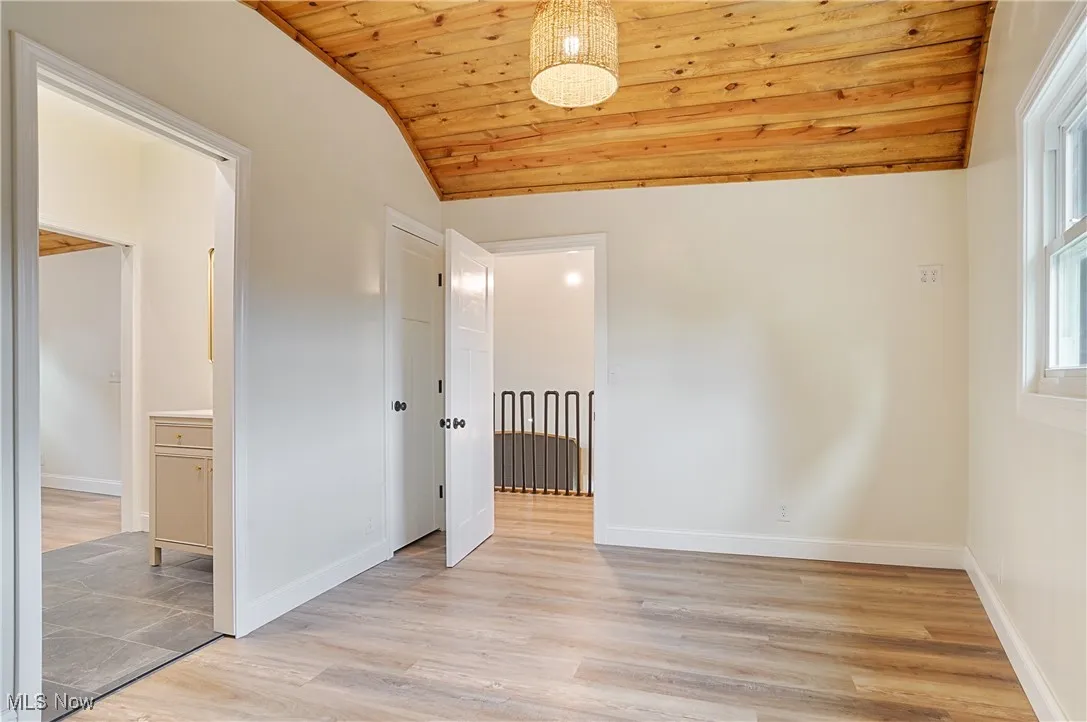 Empty room with lofted ceiling, wood ceiling, and light wood-type flooring