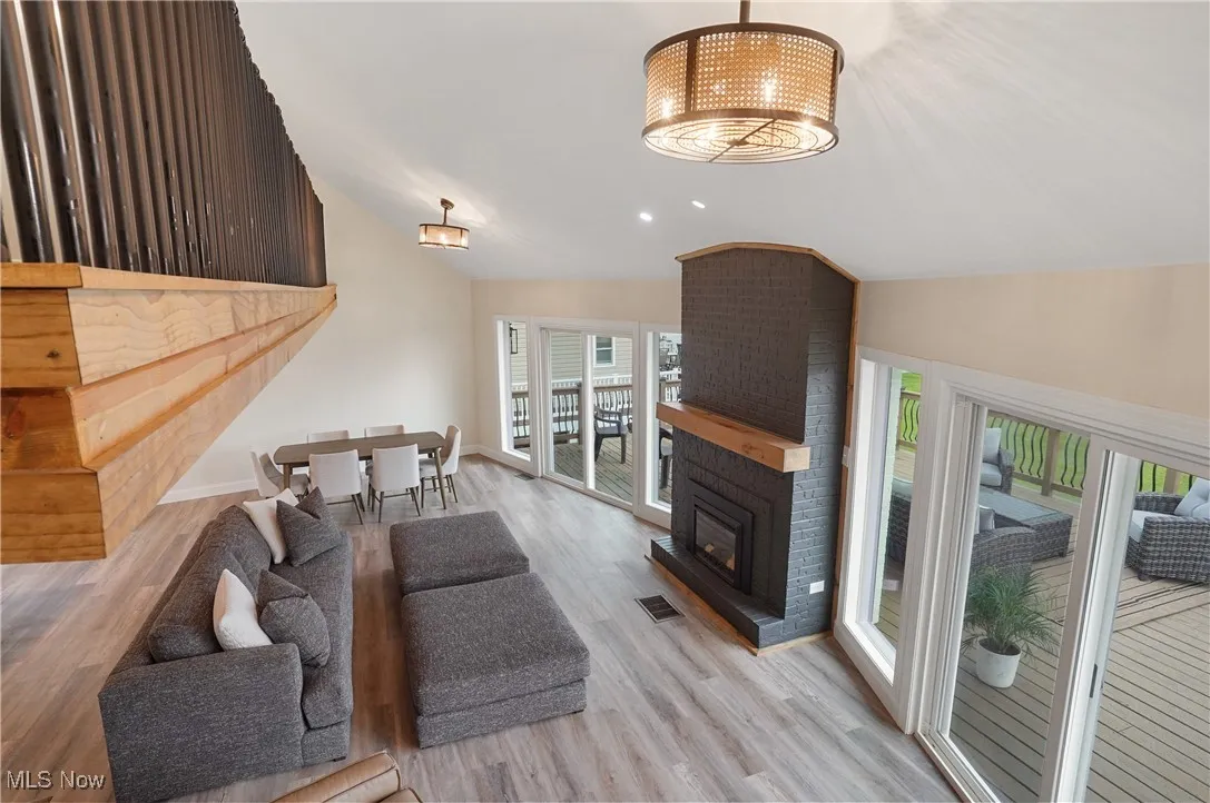 Living room featuring vaulted ceiling, wood finished floors, and a fireplace