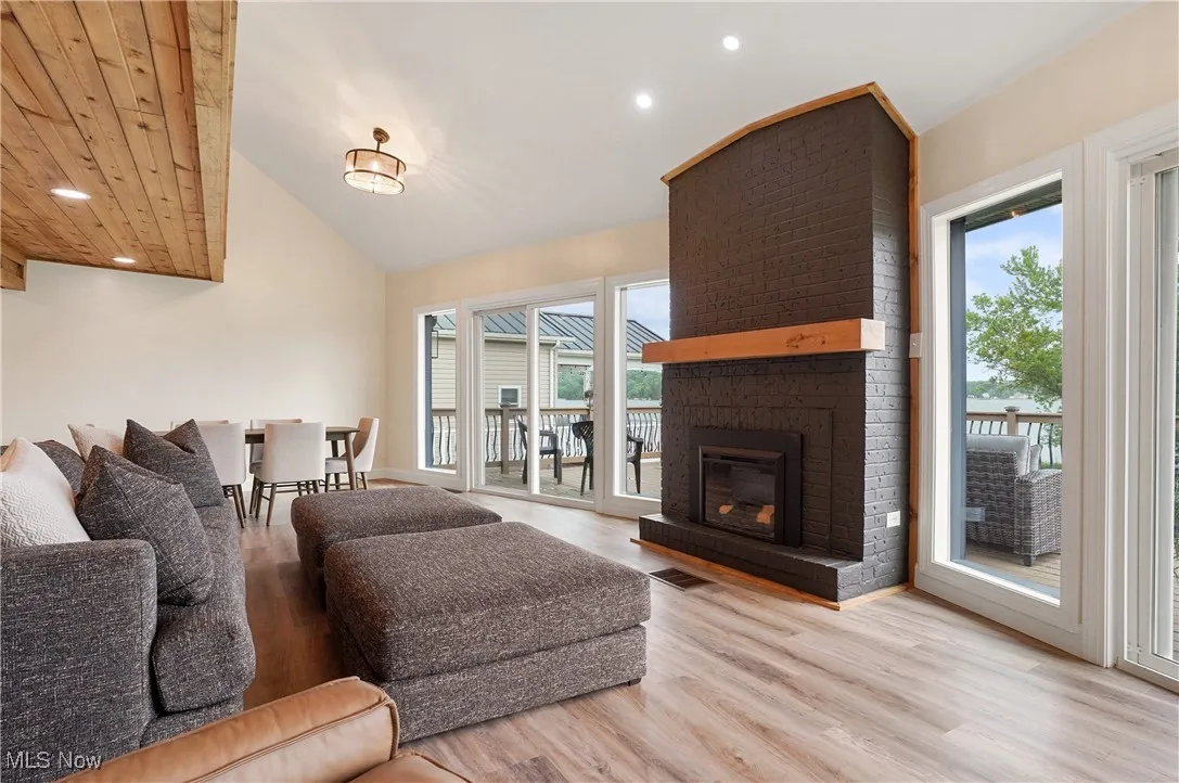 Living area with recessed lighting, wood finished floors, lofted ceiling, and a fireplace