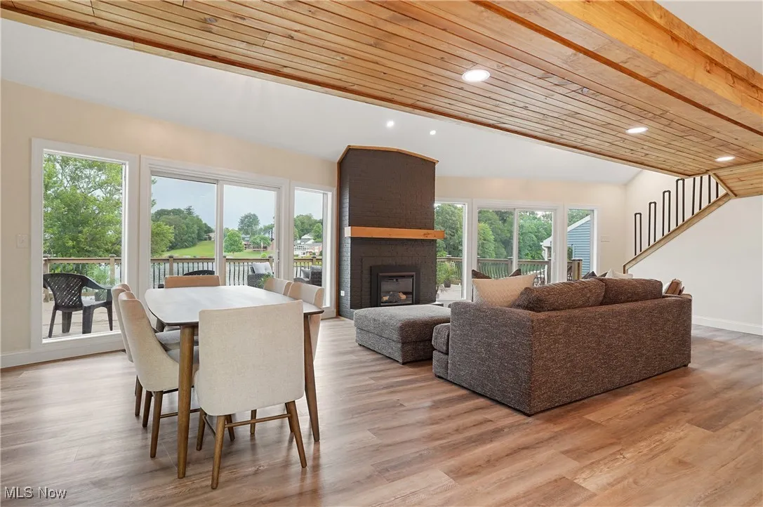 Dining room with a fireplace, lofted ceiling, recessed lighting, light wood finished floors, and wooden ceiling